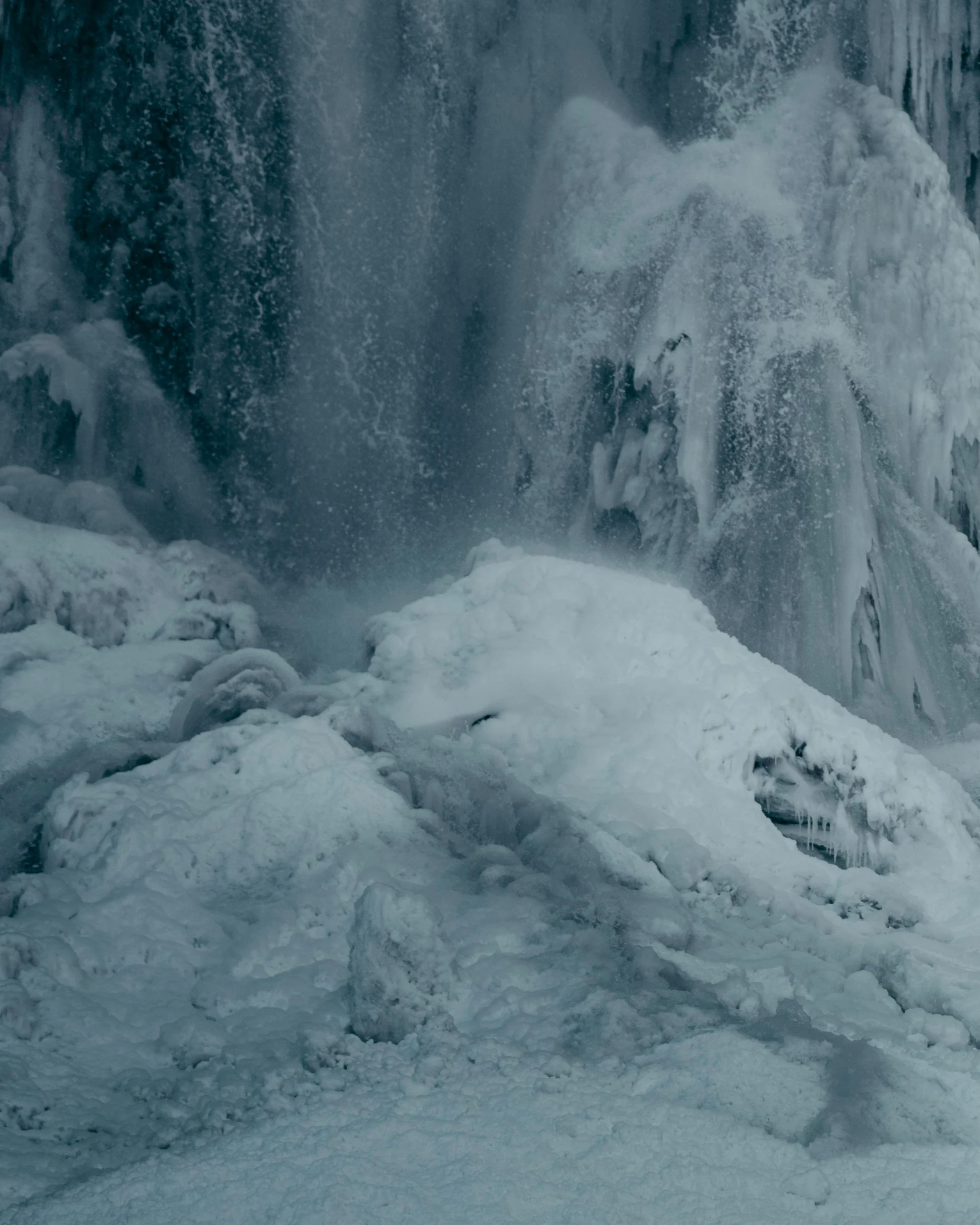 a man walking along the side of a river next to a waterfall