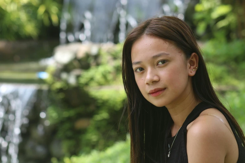 young woman looking at camera near waterfall