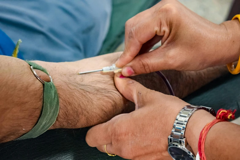 a man holding an needle with another man putting one on it