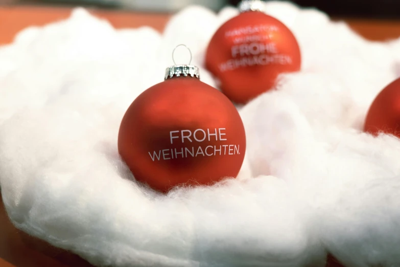 a close up of four red glass christmas ornaments with white cotton