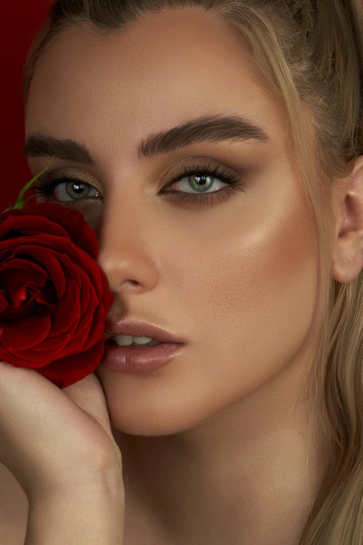 a beautiful blonde posing for a picture while holding a red rose