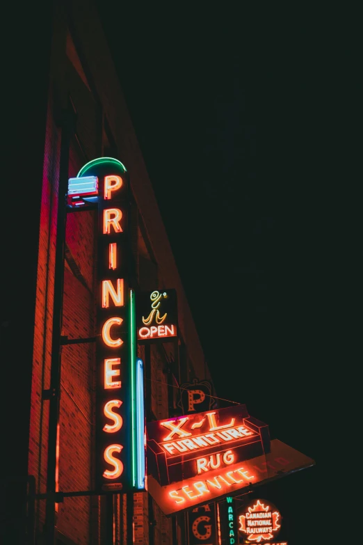 several neon signs line up against the side of a building