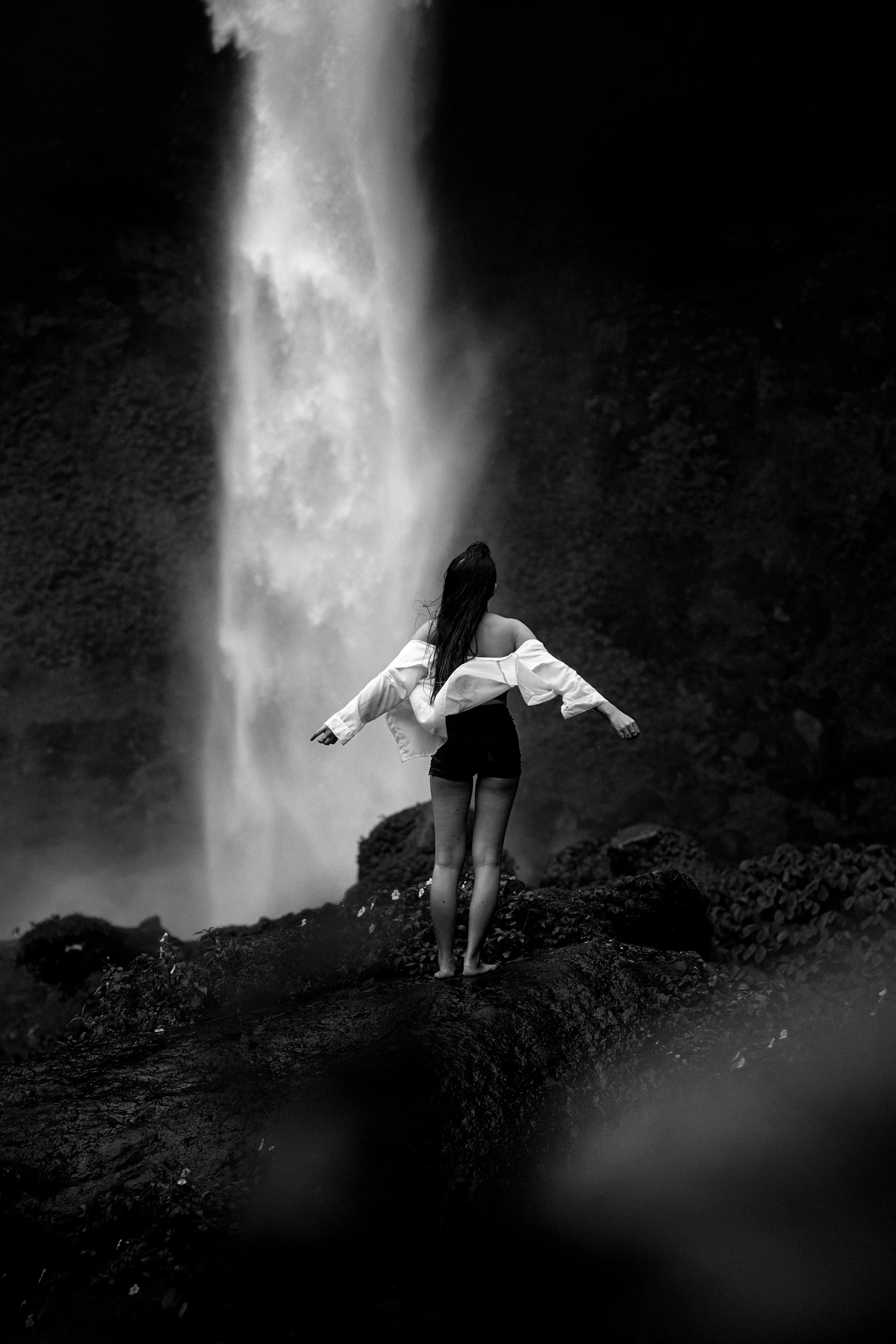 a woman is standing near a waterfall