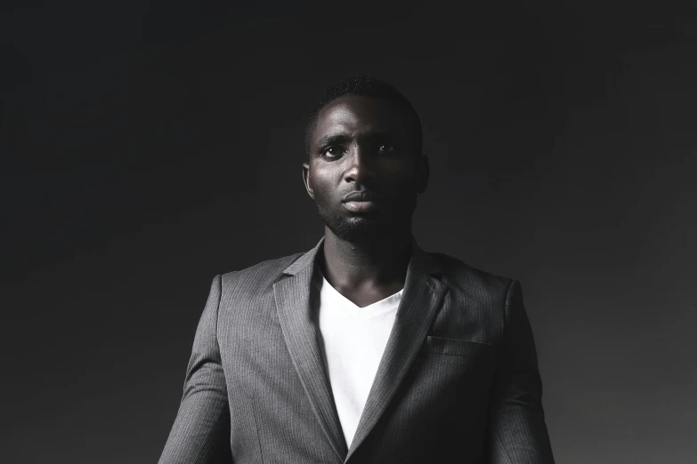 a young man is wearing a suit and standing in front of a black background