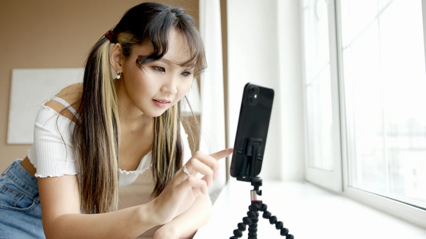 woman kneeling next to a camera looking at cell phone