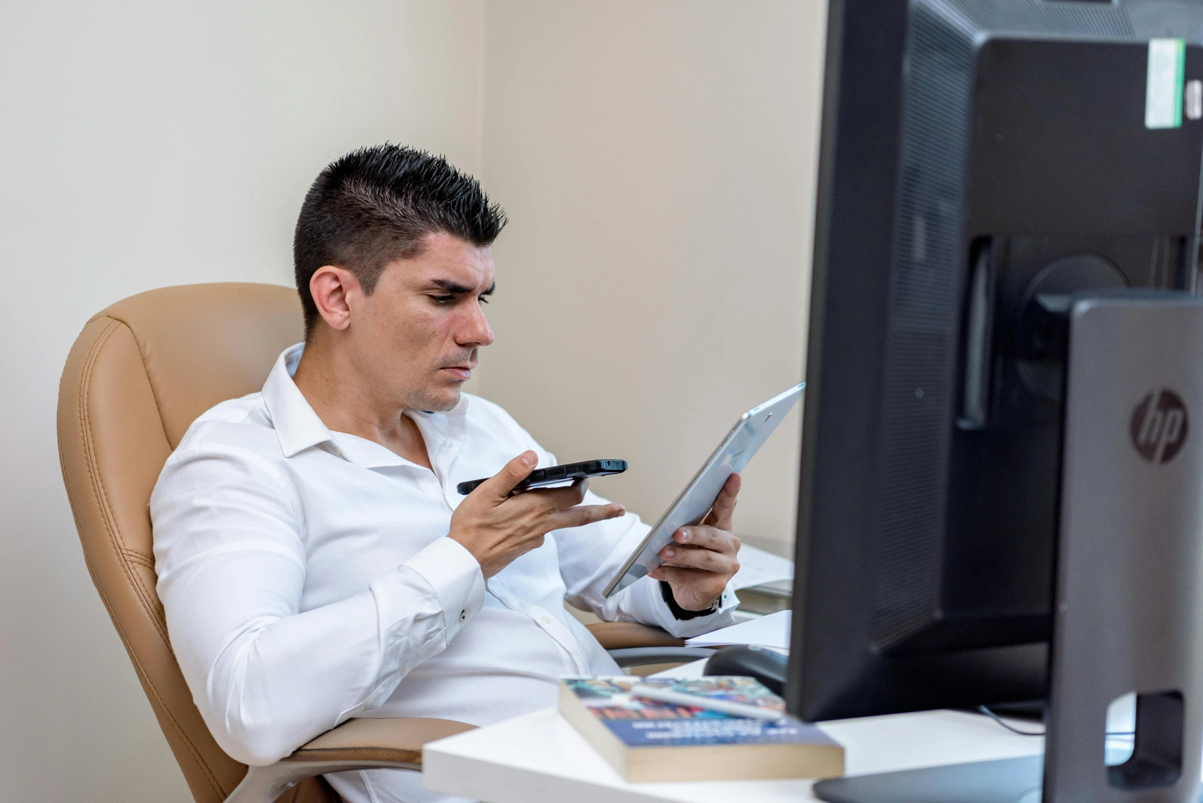 a man with a cell phone sitting in front of a computer