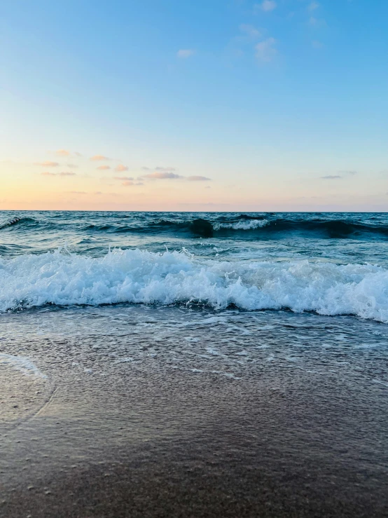 a person standing on the beach as the sun sets