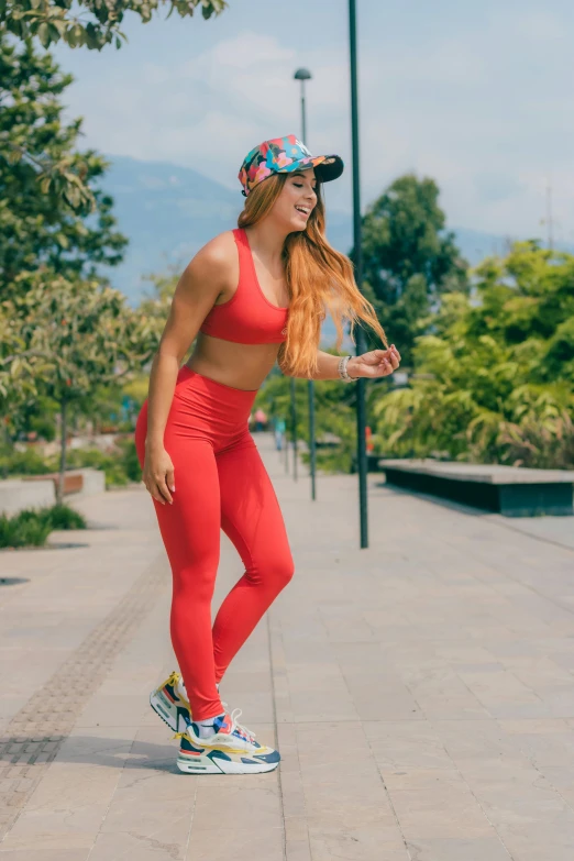 a woman in a red tank top and matching leggings with sneakers