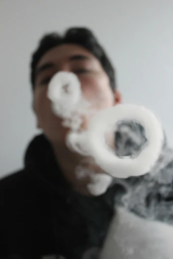 man in black shirt blowing white smoke into the air