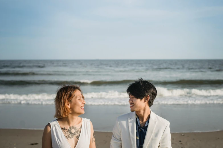 a man and woman are standing on the beach