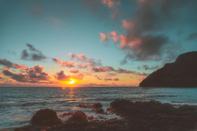 a sunset view from the shore of a large body of water