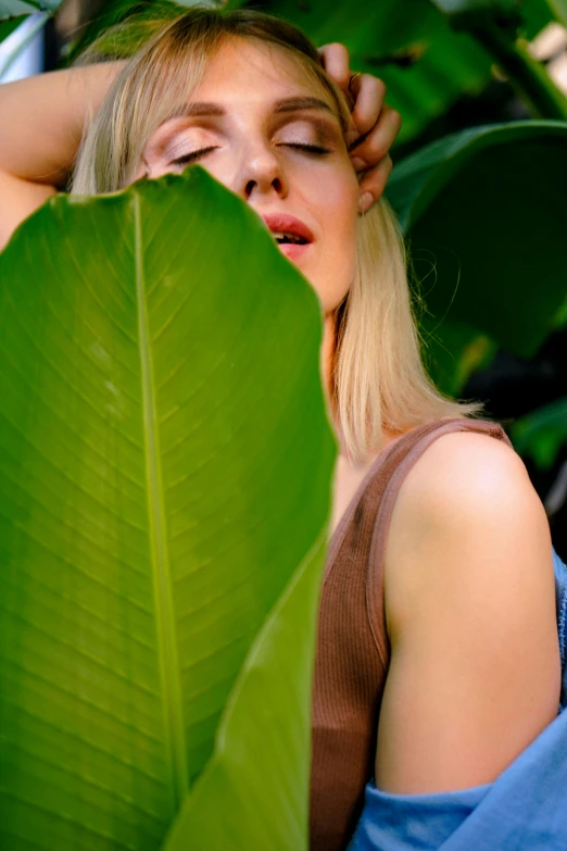 a girl laying down next to a large green leaf