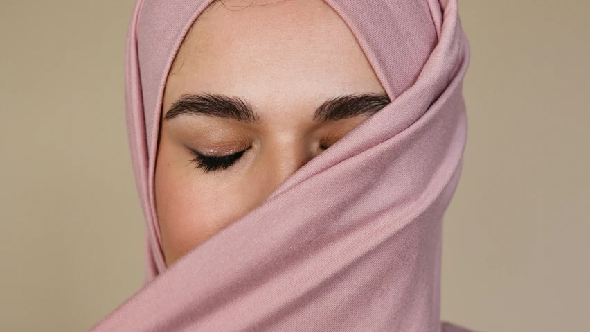 the top half of a woman with closed eyes and a pink scarf