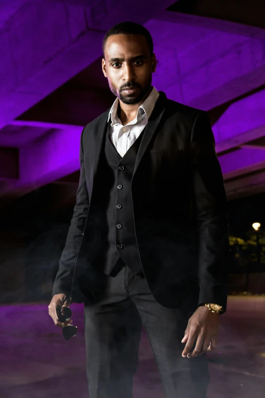 a man with a beard in a suit in front of a purple background