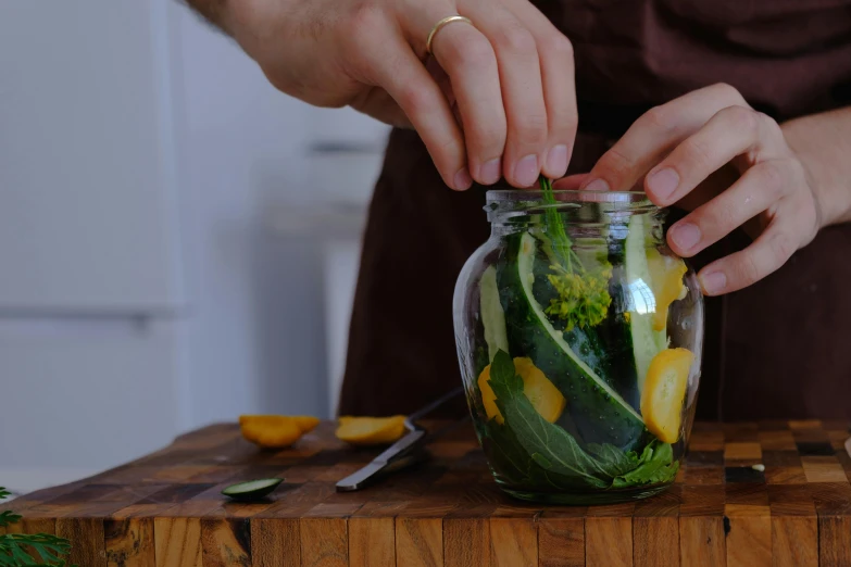 a person grabbing a pickle out of a jar filled with veggies