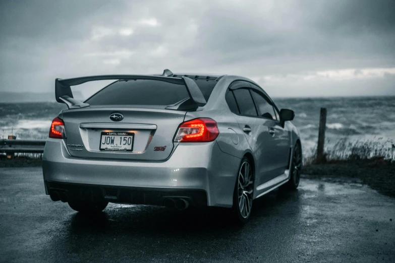 a silver subarunt parked on top of a wet road