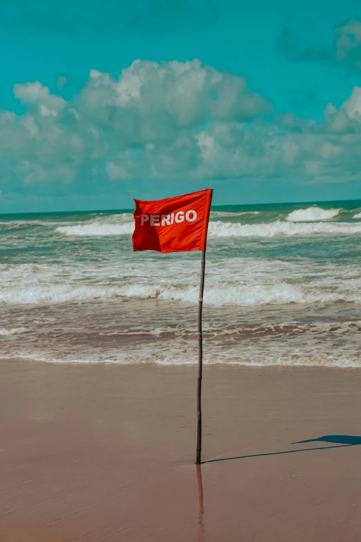 a red flag with an orange company logo on it on the beach