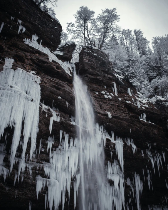 the waterfall is covered in icicles on the cliff