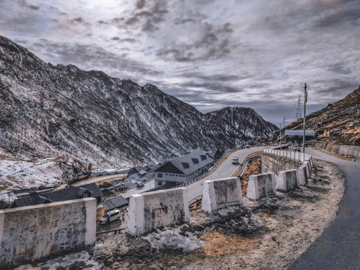 an empty road in front of mountains with a cloudy sky