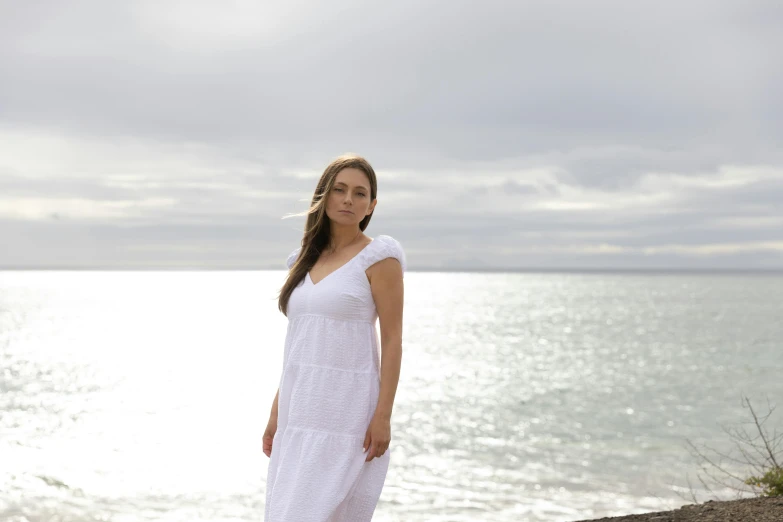 a woman standing on the beach in front of the ocean