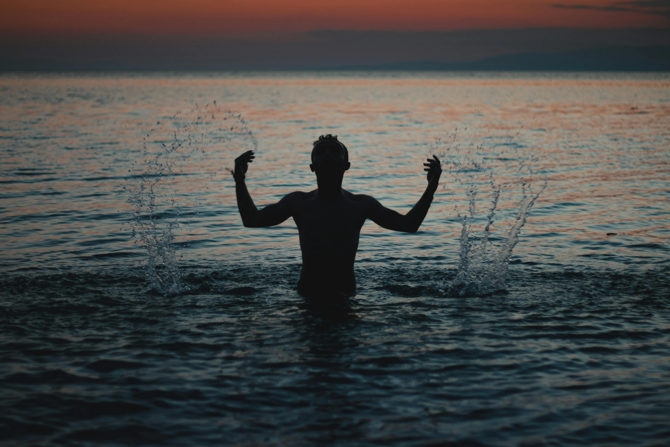 a man in the ocean reaching for the sky