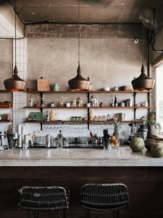 a bar with two chairs near it and shelves of bottles and jars