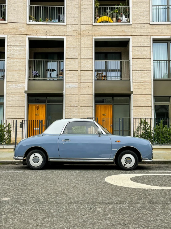 a blue car is parked on the street in front of a tan apartment building