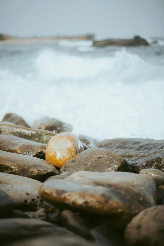 a lone orange object sits among the rocks at the beach