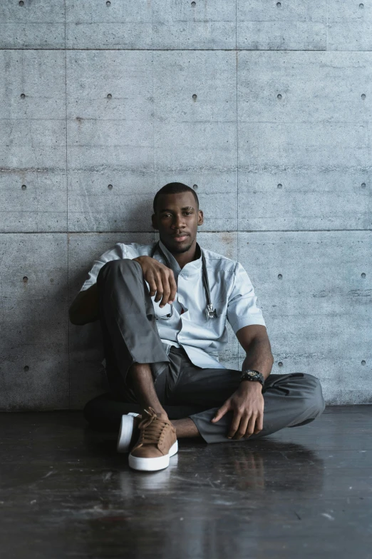 a man sitting in front of a wall wearing a white shirt