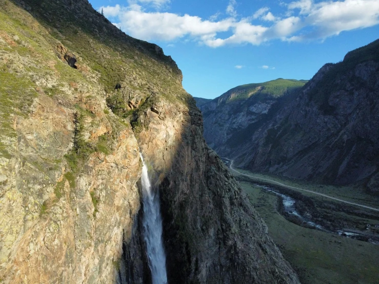 a waterfall surrounded by mountains with water flowing over the edge