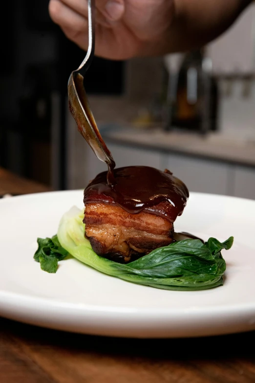 a chef is spreading sauce on a dish that has a green pea leaf on it