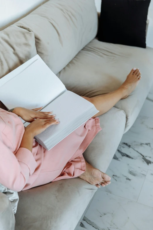 a person laying on the couch and reading a book