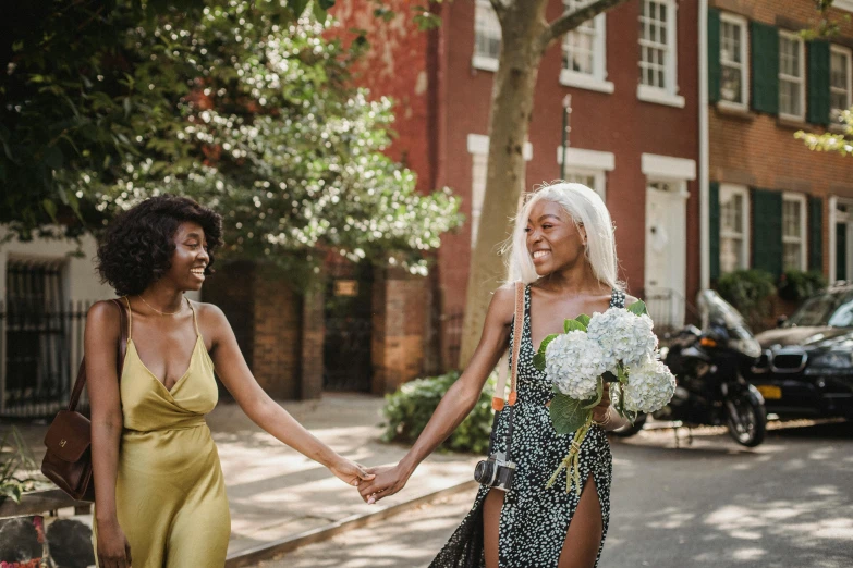 a couple of women are walking down the street holding hands