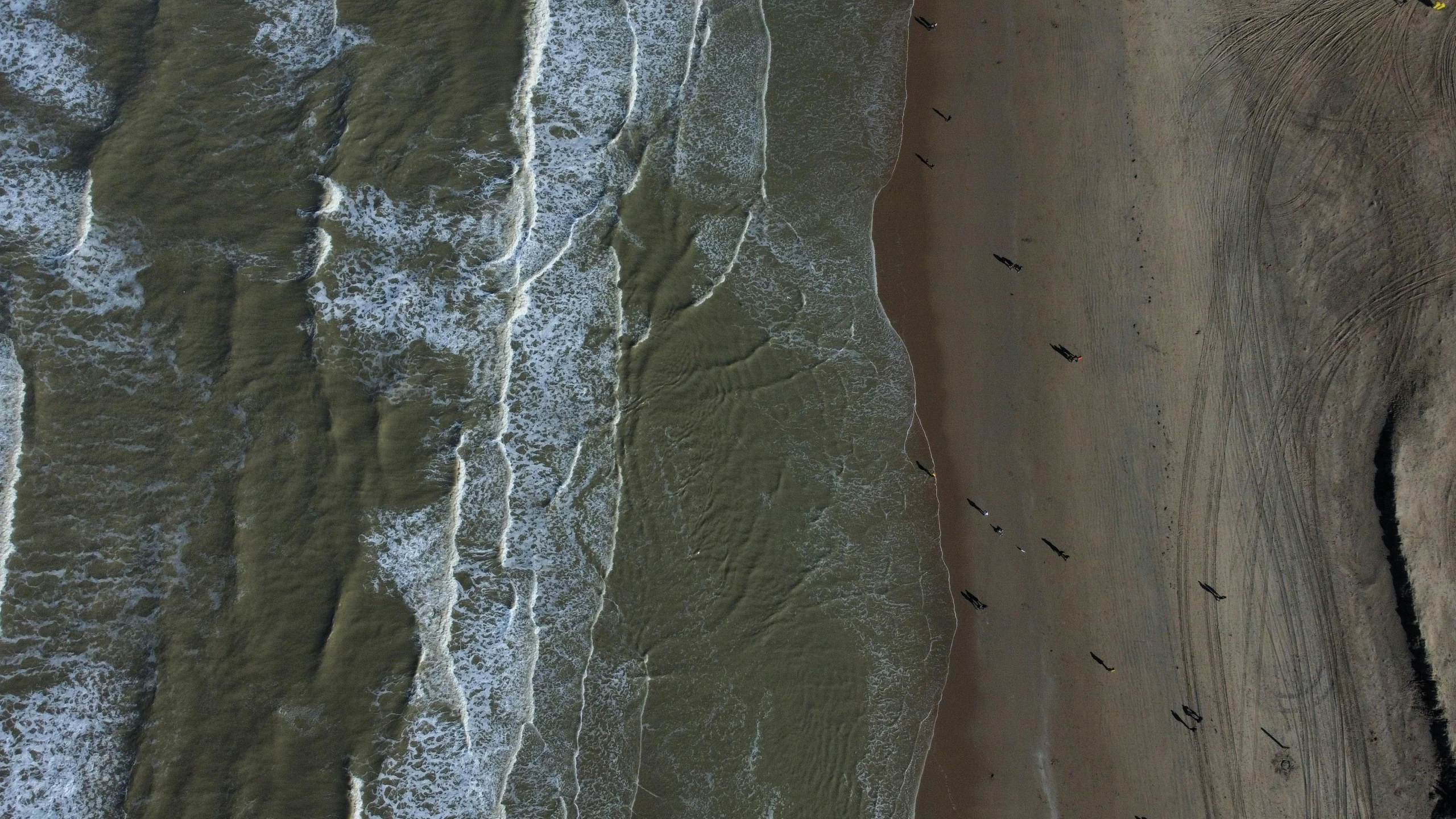 an aerial view of ocean waves next to a beach