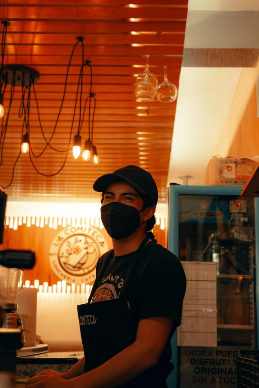 a man wearing a black face mask in a kitchen