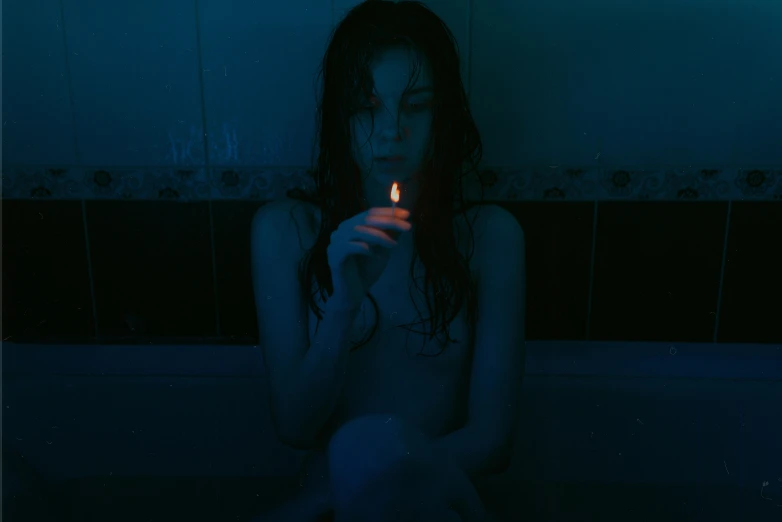 a women who is holding a candle in the bathroom