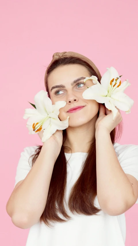 the girl holds two flowers over her eyes