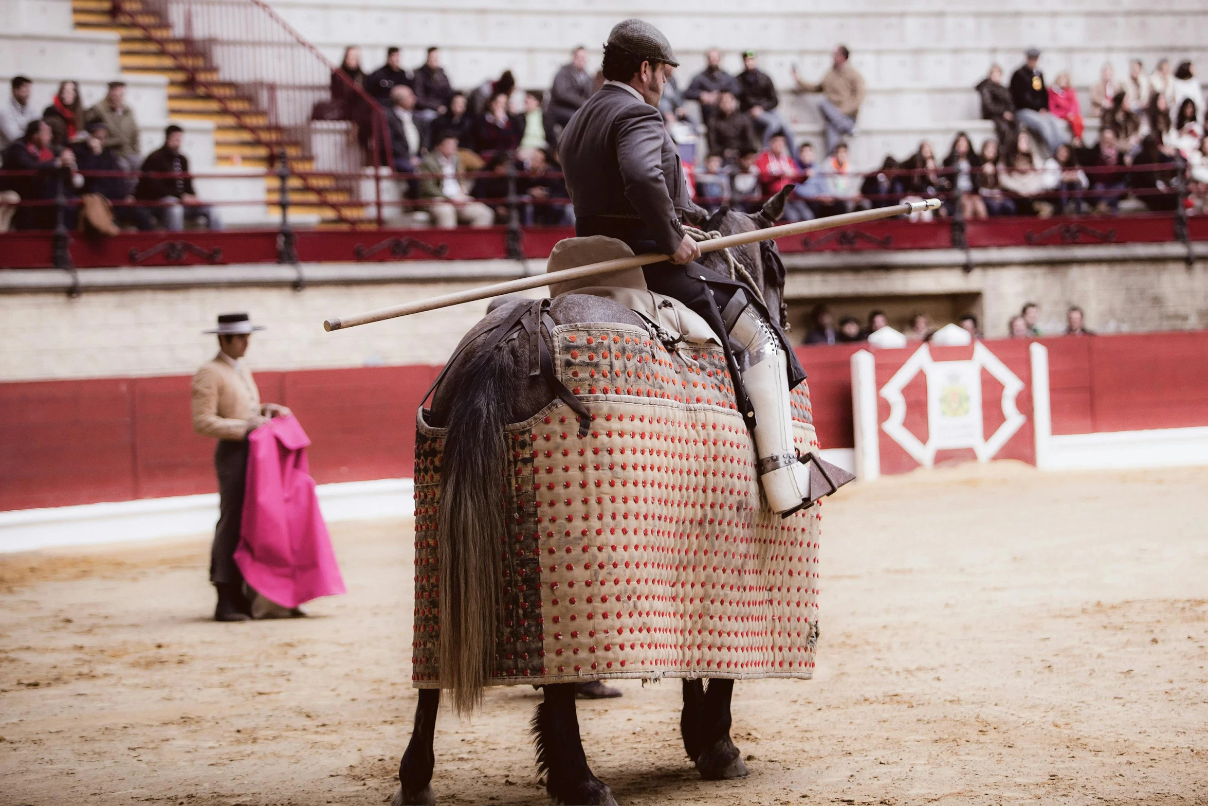 man on horse with spear and inflatable helmet riding by with spectators