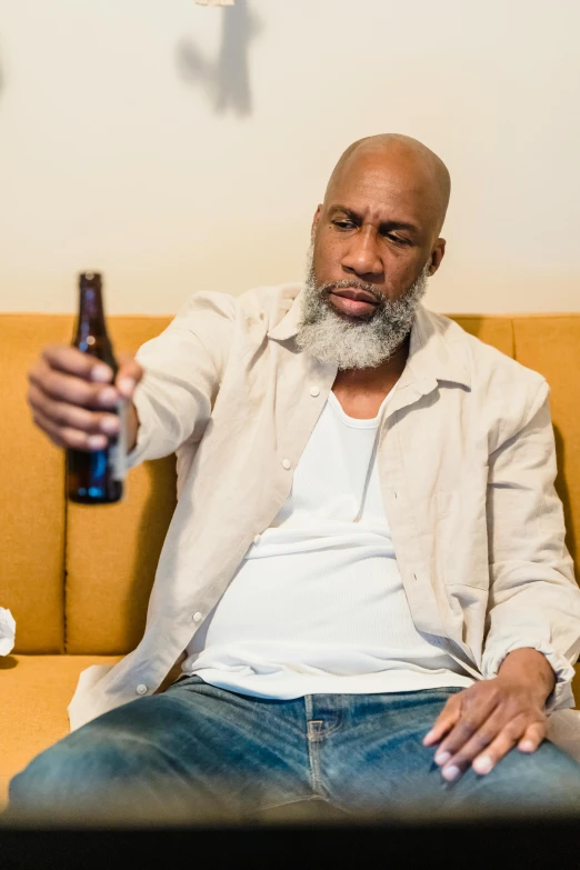 a man sitting on a couch holding a beer