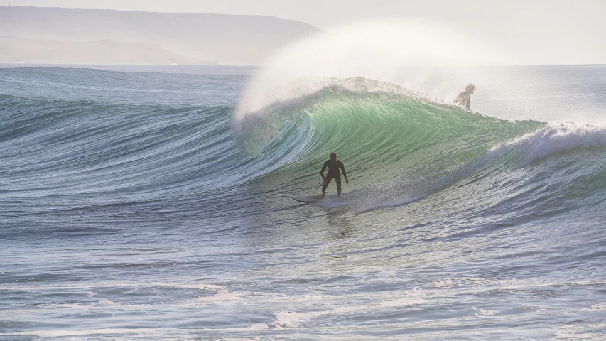 a surfer riding the top of an ocean wave