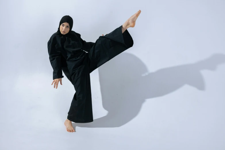 a person in a black outfit on white background doing a trick