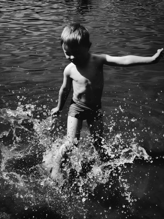 a little boy standing on top of a river