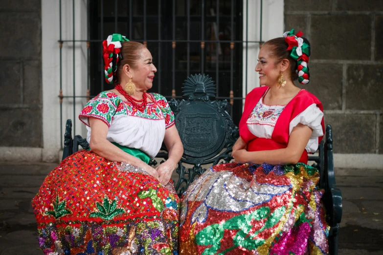 two woman sitting next to each other with an iron gate