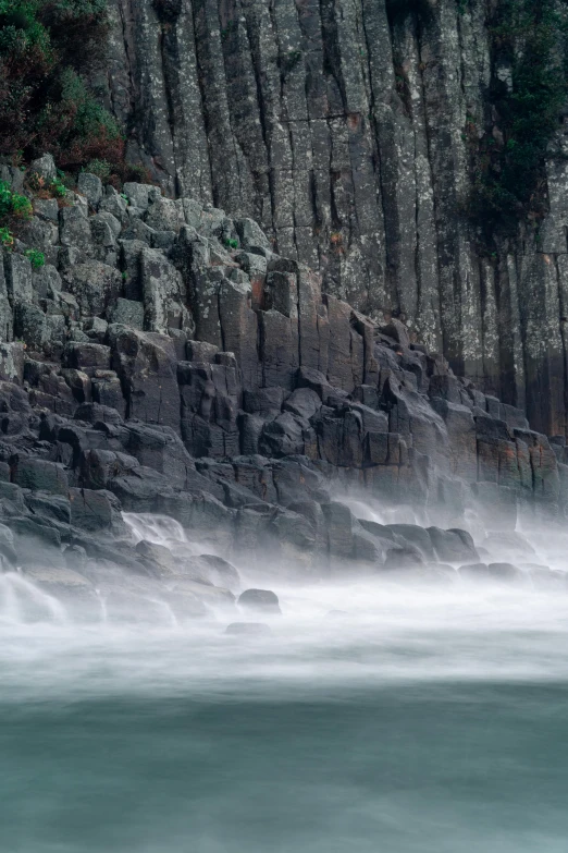 a rocky cliff face with water splashing through