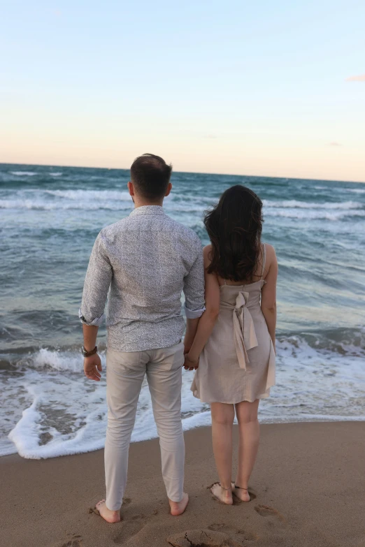 a couple standing on the beach holding hands