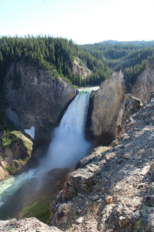 a tall waterfall surrounded by mountains and forest