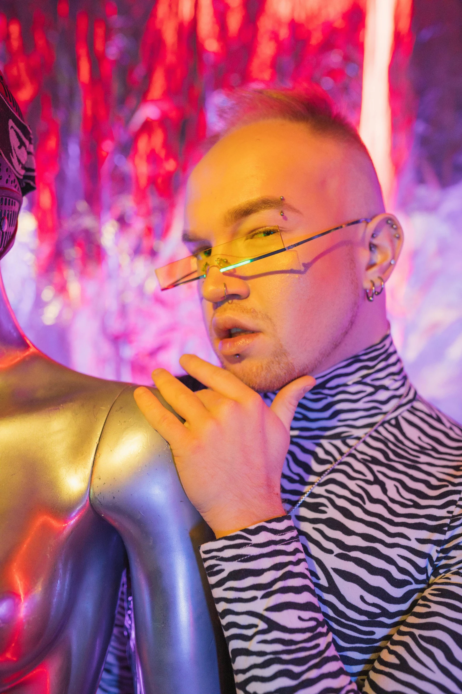 a man poses with his arm around the torso of a sculpture