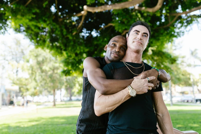 two men hug while standing in a park