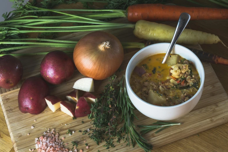 bowl of soup next to some veggies and potatoes