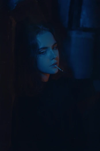 a young woman is smoking in the dark